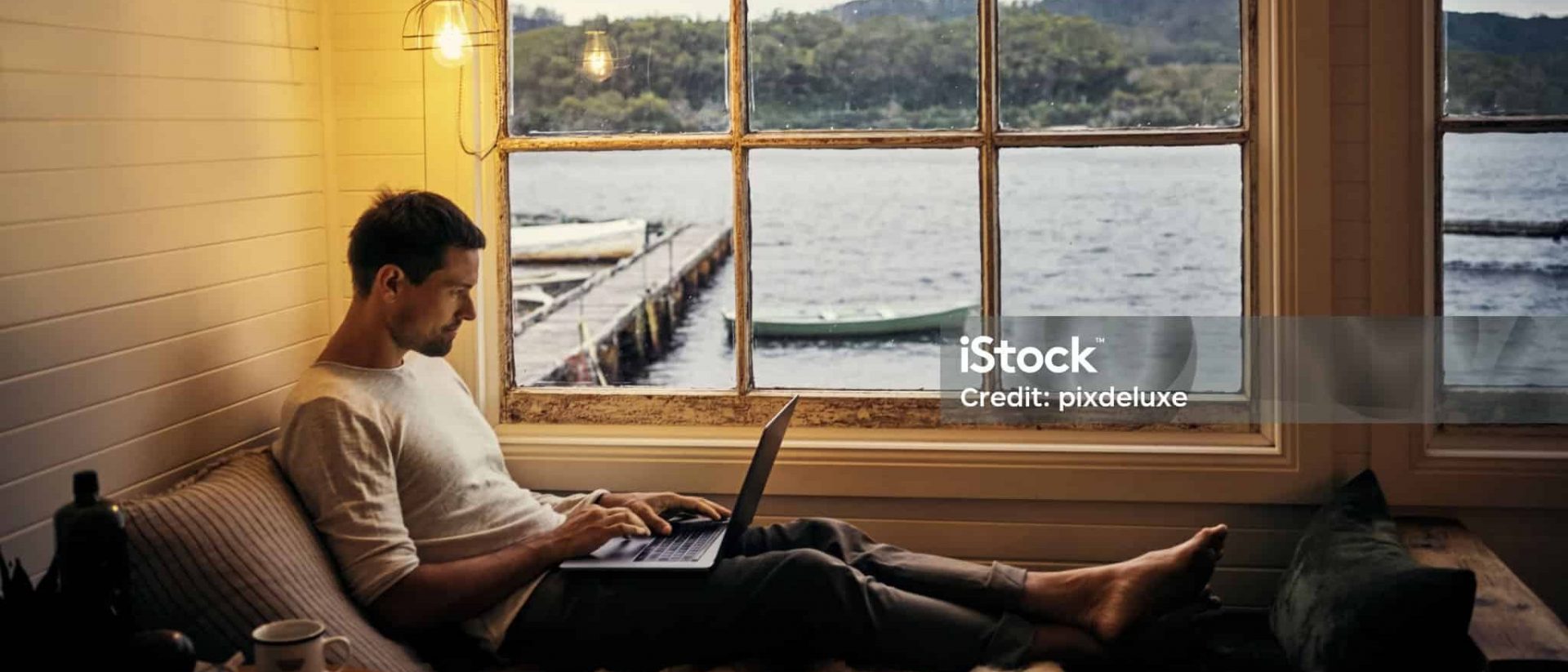 Shot of a young man using a laptop while relaxing in his holiday home